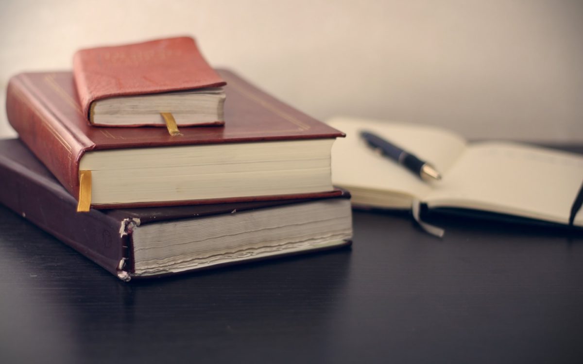 selective focus photography of three books beside opened notebook
