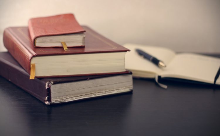 selective focus photography of three books beside opened notebook