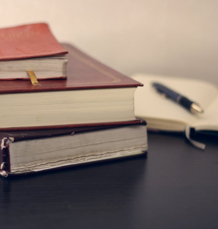 selective focus photography of three books beside opened notebook