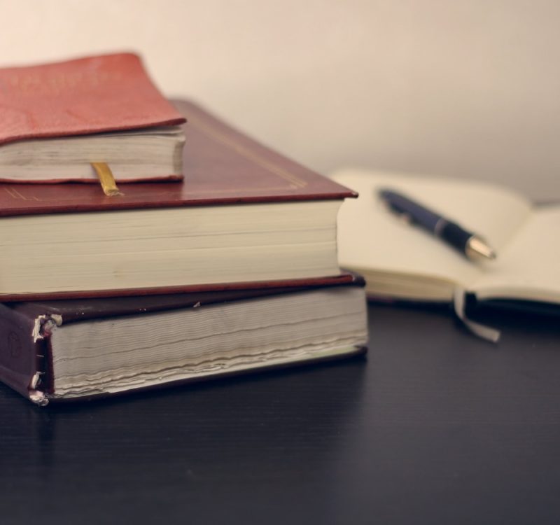 selective focus photography of three books beside opened notebook